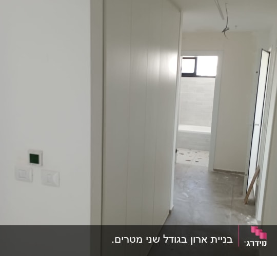 מסדרון עם ארון קיר לבן ודלת פתוחה